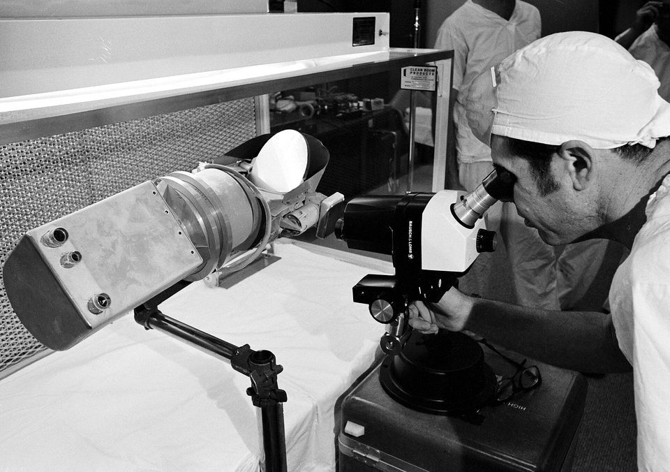 View of scientist looking at a Surveyor III components with a microscope in a Lunar Receiving Laboratory sterile vacuum cabinet (s70-22401)